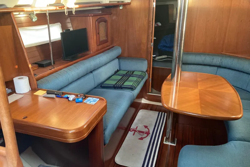 Slide: The Image of Interior of 2000 Beneteau Oceanis 361 sailboat with wooden furnishings and blue seating. - 13