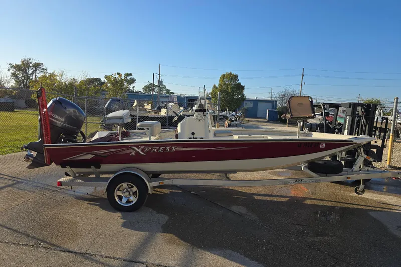 Slide: The Image of 2013 Xpress H20B Bay boat on trailer, parked outdoors under clear blue sky. - 5