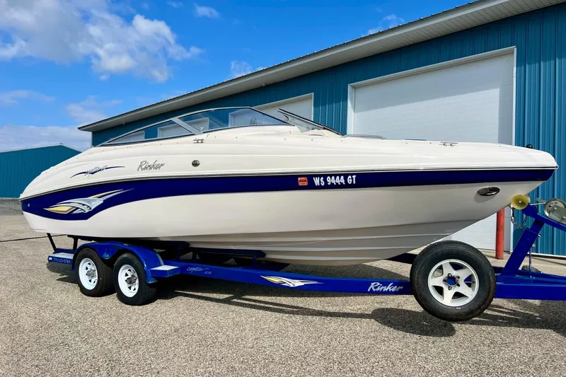The Image of 2004 Rinker 232 Captiva Bowrider on trailer, parked near blue building. - 0