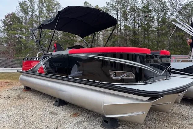 Slide: The Image of 2026 Tahoe Pontoon LTZ 2385 VRB Tritoon with red and black design, parked outdoors. - 3