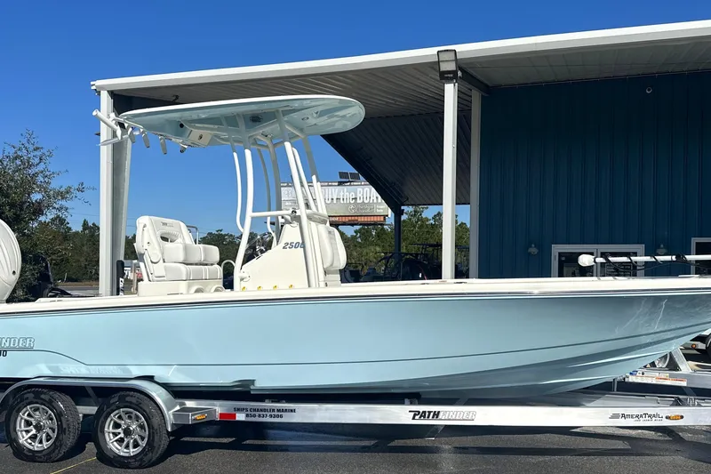 Slide: The Image of 2026 Pathfinder 2500 Hybrid boat on trailer, parked outside a blue building. - 24