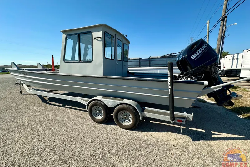 The Image of 2024 SeaArk 2672 Workhorse boat with Suzuki outboard motor on a trailer. - 1