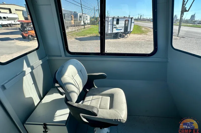 Slide: The Image of Interior of 2024 SeaArk 2672 Workhorse boat with a cushioned chair and window view. - 13