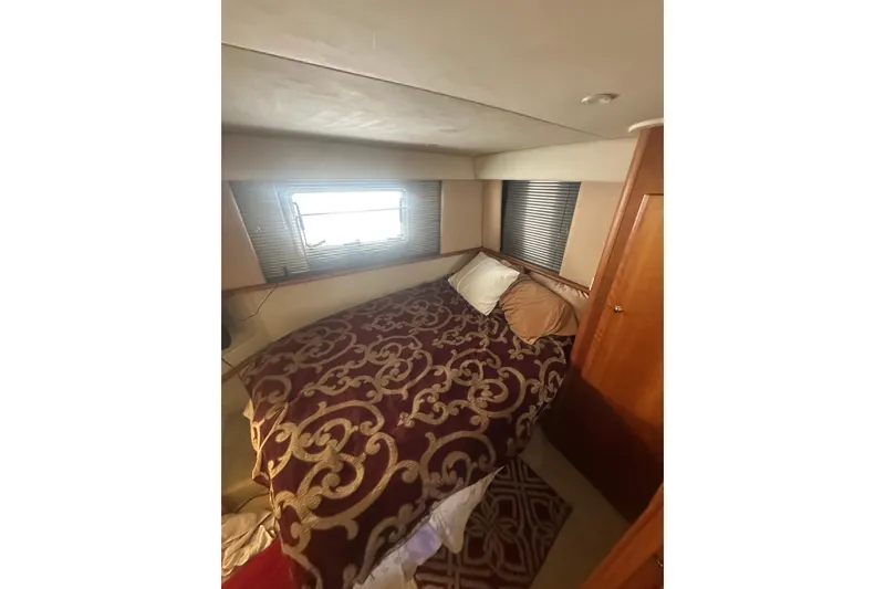 Slide: The Image of Cozy bedroom interior of 2000 Silverton 38 yacht with patterned bedding and window blinds. - 15
