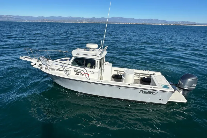 Slide: The Image of 2020 Parker 2320 Sport Cabin boat on open water, clear sky, distant mountains. - 2