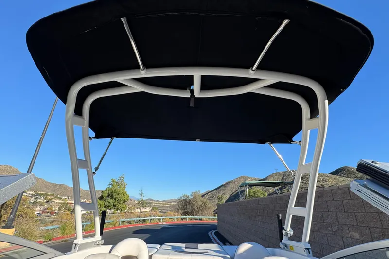 Slide: The Image of 2019 Chaparral 21 H2O Ski & Fish boat with black bimini top, scenic mountain backdrop. - 15