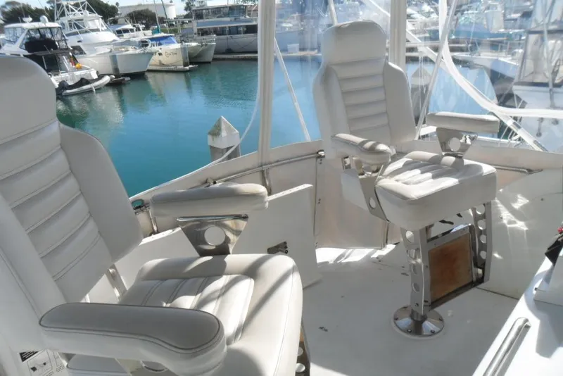 Slide: The Image of 1979 Bertram 46.6 Sport Fisher cockpit with white captain chairs in marina setting. - 13