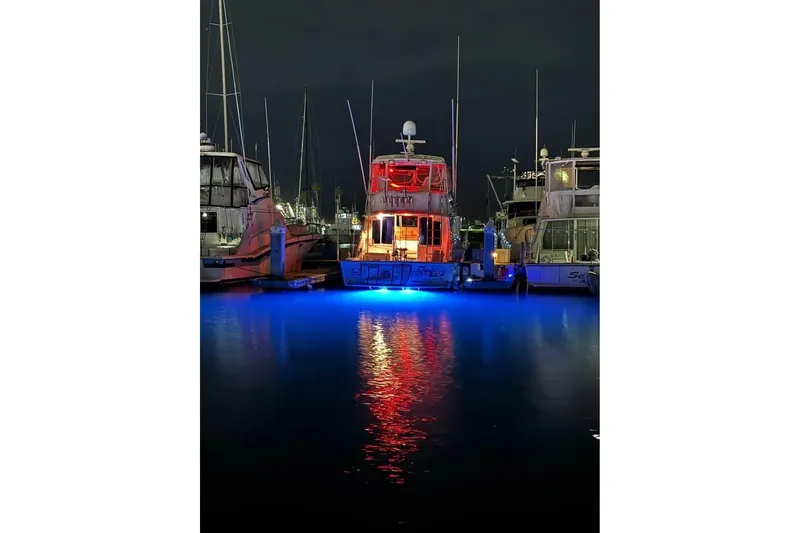 Slide: The Image of 1979 Bertram 46.6 Sport Fisher with vibrant blue and red lights at night. - 19