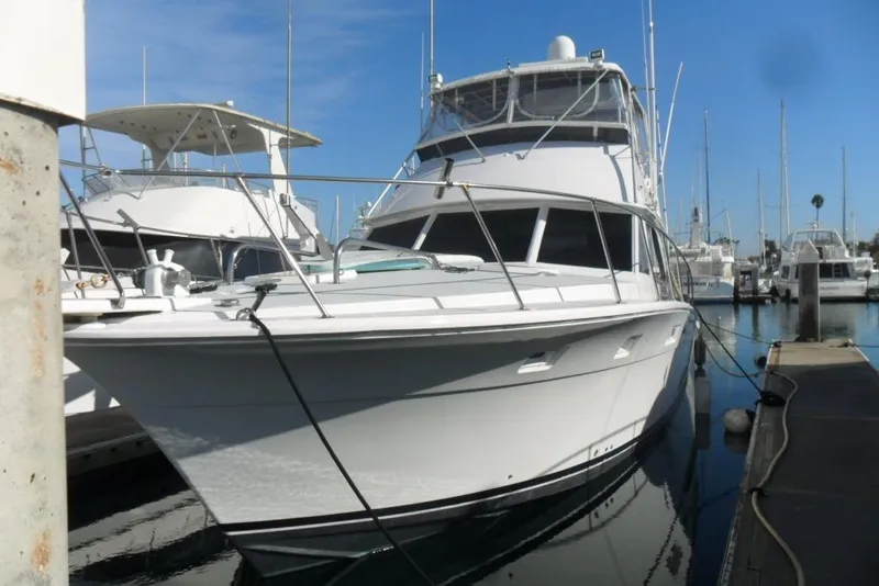 Slide: The Image of 1979 Bertram 46.6 Sport Fisher yacht docked in a marina under clear blue skies. - 3