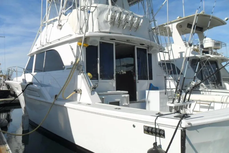 Slide: The Image of 1979 Bertram 46.6 Sport Fisher yacht docked, featuring fishing rods and spacious deck. - 4