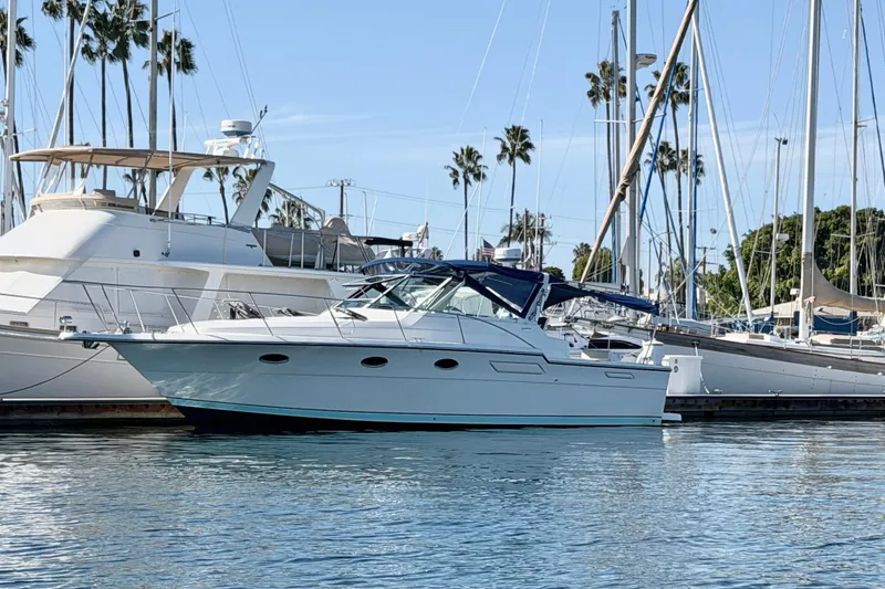 The Image of 1990 Tiara Open yacht docked in a marina with sailboats and palm trees. - 0