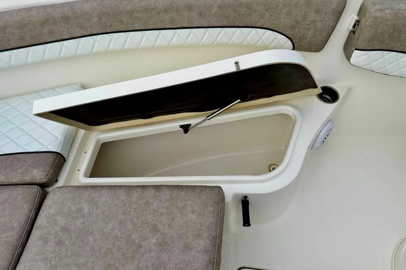 Slide: The Image of 2016 NauticStar 28 XS boat storage compartment with cushioned seating and open hatch. - 15
