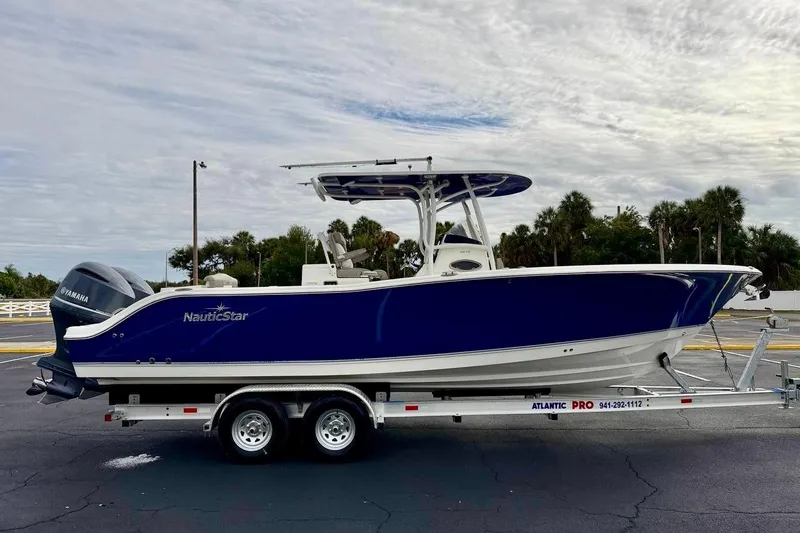 Slide: The Image of 2016 NauticStar 28 XS boat on trailer, blue hull, parked outdoors. - 4