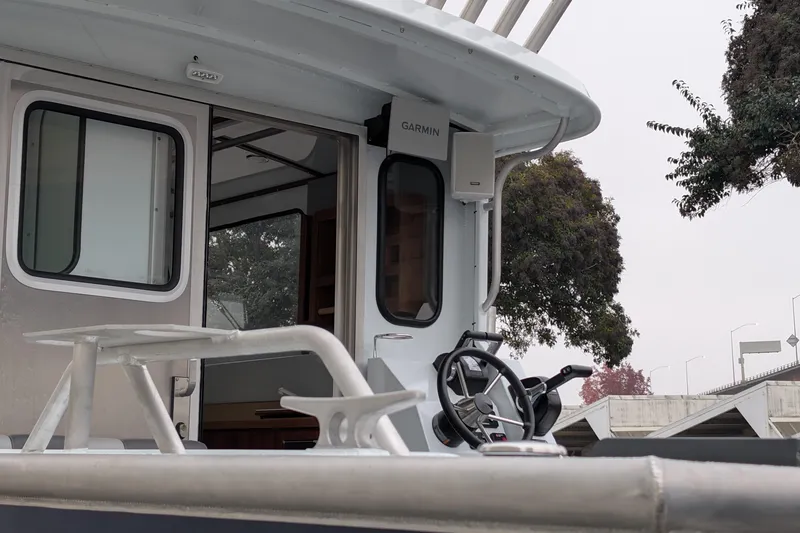 Slide: The Image of 2022 Hewscraft Pacific Explorer boat with Garmin equipment, docked near trees. - 13