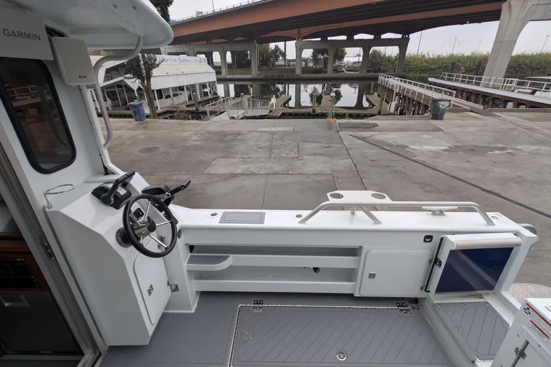 Slide: The Image of 2022 Hewscraft Pacific Explorer boat interior at dockside, featuring steering console and open deck. - 19