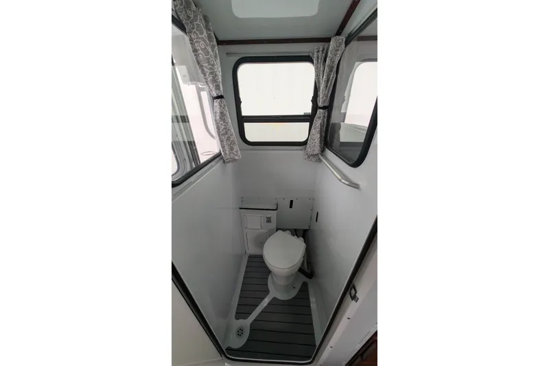 Slide: The Image of 2022 Hewscraft Pacific Explorer boat interior bathroom with toilet and windows. - 28