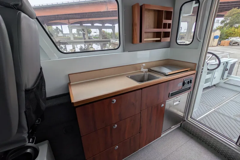 Slide: The Image of Interior of 2022 Hewscraft Pacific Explorer boat with kitchenette and seating area. - 29