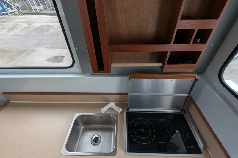 Slide: The Image of 2022 Hewscraft Pacific Explorer kitchen with sink, electric stove, and wooden storage shelves. - 30