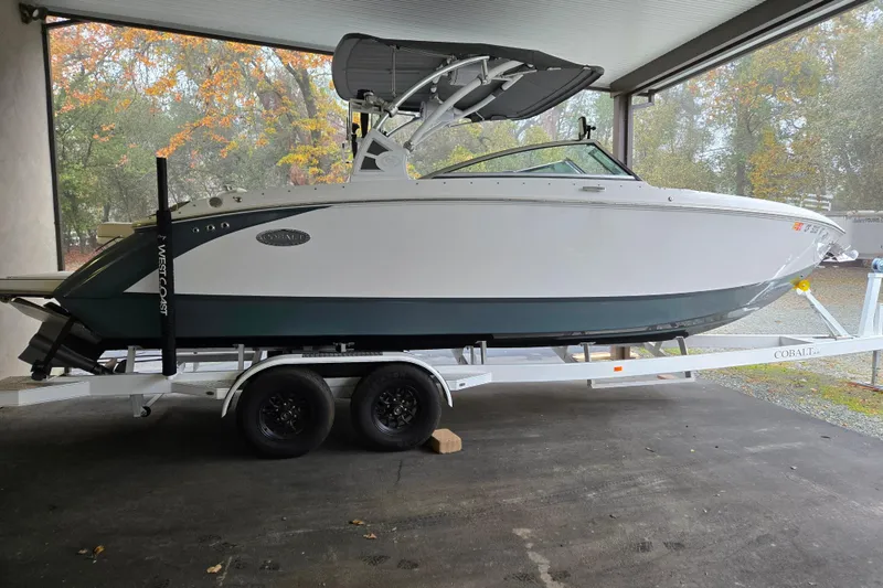 Slide: The Image of 2020 Cobalt R7 Surf boat on trailer, parked indoors with autumn trees in background. - 1