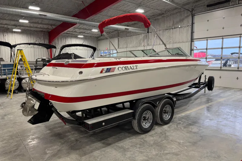 Slide: The Image of 1995 Cobalt 252 boat with red accents on a trailer in a garage. - 14