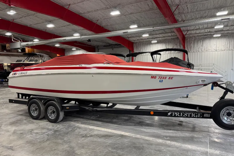 Slide: The Image of 1995 Cobalt 252 boat with red cover on trailer in indoor storage. - 19