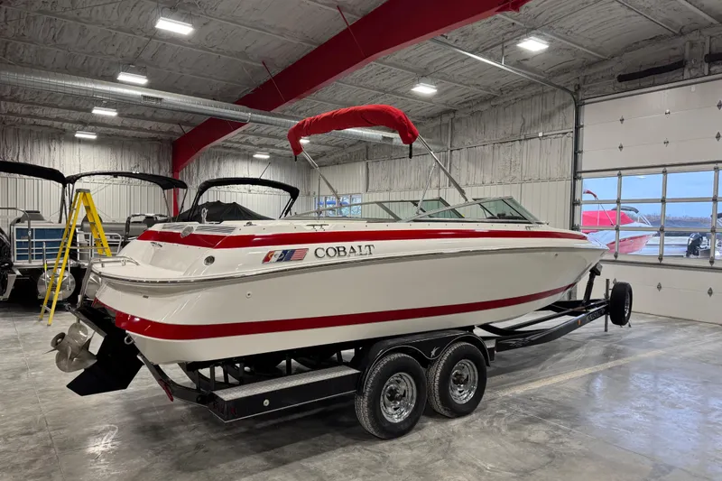 Slide: The Image of 1995 Cobalt 252 boat with red accents on a trailer in a garage. - 4