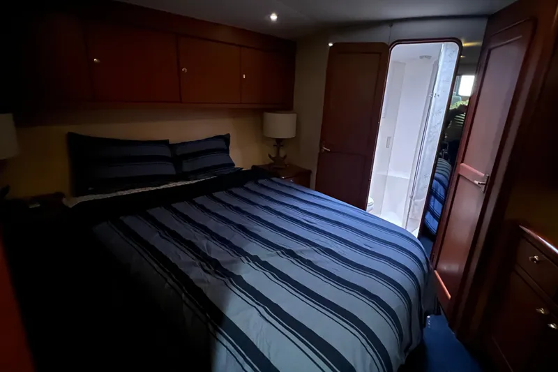 Slide: The Image of Bedroom interior of 1999 Ocean Yachts 56 Super Sport with striped bedding and ensuite bathroom. - 22