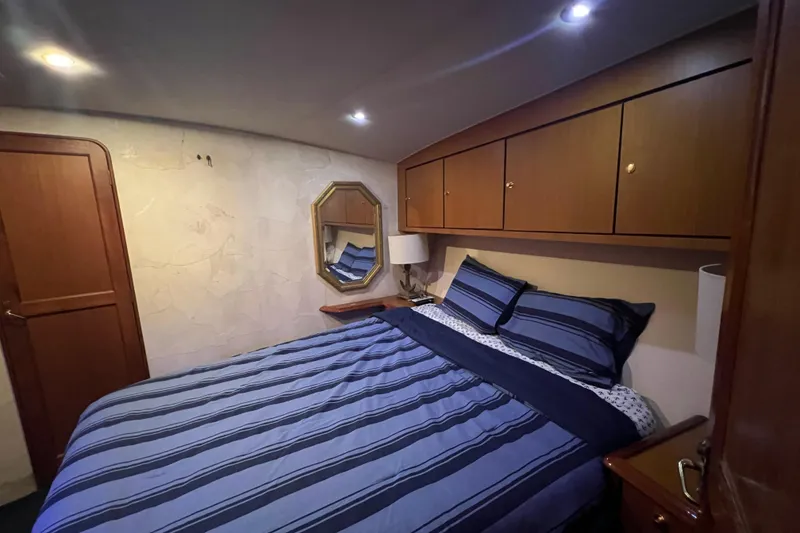 Slide: The Image of Bedroom interior of 1999 Ocean Yachts 56 Super Sport with striped bedding and wooden cabinets. - 45