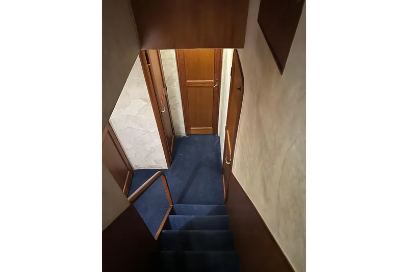 Slide: The Image of Stairway inside 1999 Ocean Yachts 56 Super Sport, featuring wooden doors and blue carpet. - 50