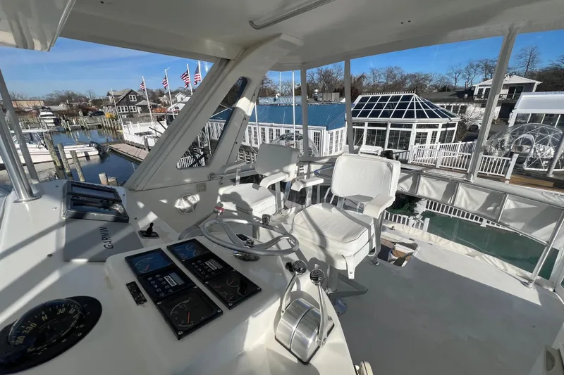 Slide: The Image of 1999 Ocean Yachts 56 Super Sport helm with marina view, featuring navigation instruments and seating. - 14