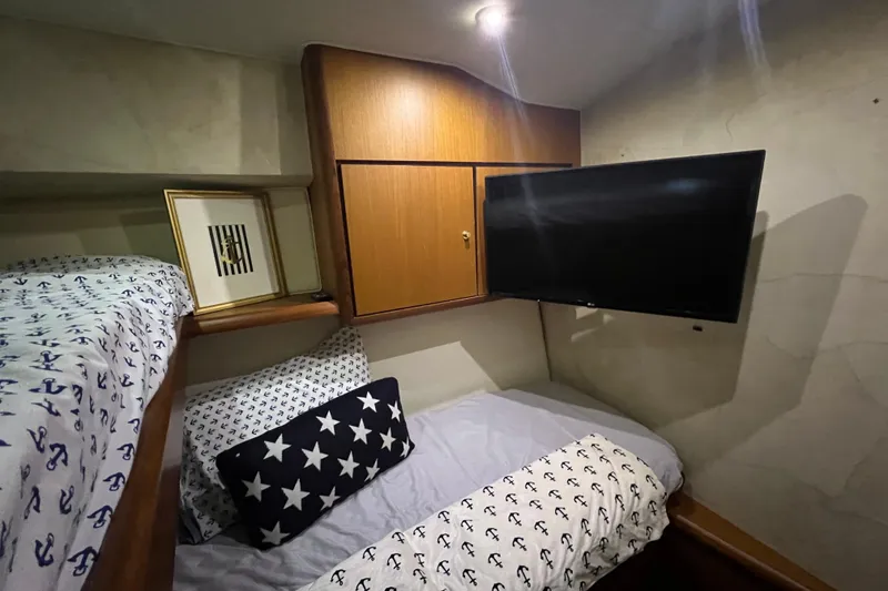 Slide: The Image of Cozy cabin interior of 1999 Ocean Yachts 56 Super Sport with nautical-themed bedding and wall-mounted TV. - 35