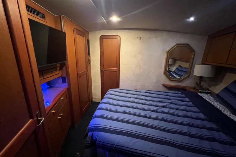 Slide: The Image of Luxurious bedroom interior of 1999 Ocean Yachts 56 Super Sport with striped bedding and wooden cabinetry. - 44