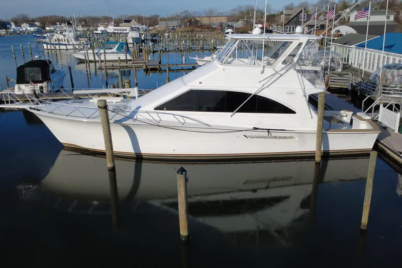 Slide: The Image of 1999 Ocean Yachts 56 Super Sport docked at a marina, reflecting on calm water. - 7