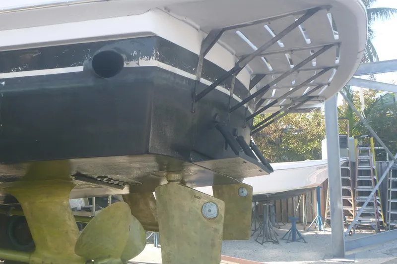 Slide: The Image of 1999 Hatteras 52 Sport Deck Motor Yacht under maintenance, showcasing propellers and hull details. - 11