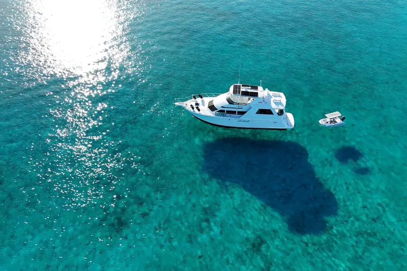 Slide: The Image of Aerial view of 1999 Hatteras 52 Sport Deck Motor Yacht on clear turquoise water. - 2