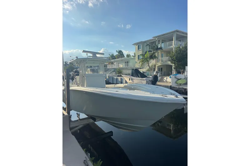 Slide: The Image of 2012 Yellowfin 32 Offshore boat docked near waterfront homes under a clear sky. - 0
