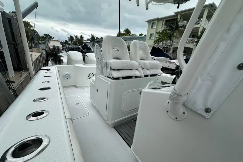 Slide: The Image of 2012 Yellowfin 32 Offshore boat with white seating and rod holders, docked near waterfront homes. - 5