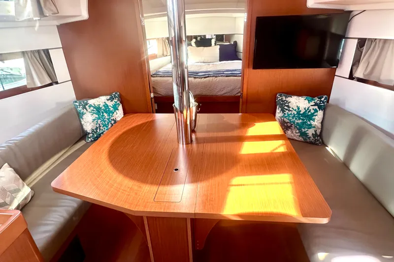 Slide: The Image of 2019 Beneteau Oceanis 38.1 interior with dining area, cushions, and TV. - 11
