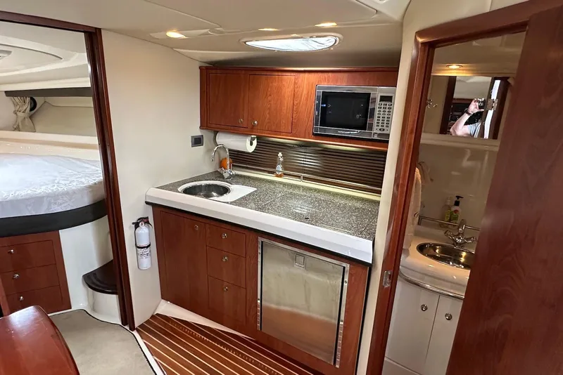 Slide: The Image of 2009 Monterey 350 Sport Yacht interior with kitchenette, featuring wood cabinetry and modern appliances. - 28