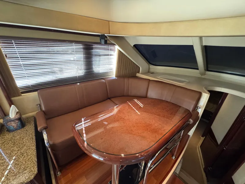 Slide: The Image of Luxurious interior of 2007 Sea Ray 52 Sedan Bridge with leather seating and wooden table. - 25