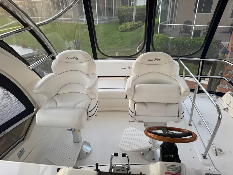 Slide: The Image of 2007 Sea Ray 52 Sedan Bridge helm with white captain chairs and wooden steering wheel. - 9
