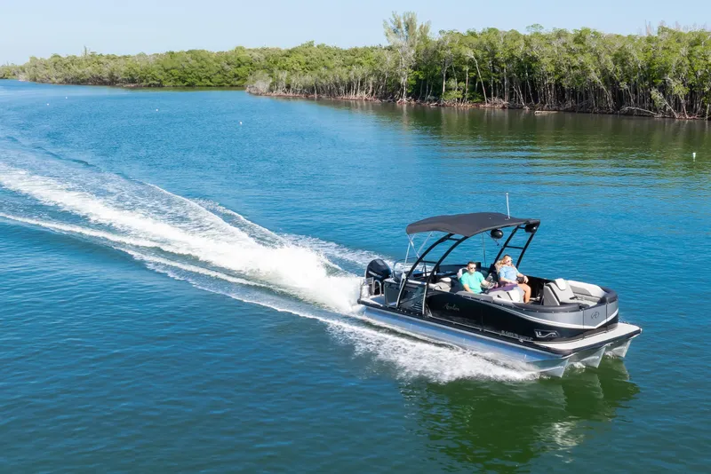 Slide: The Image of 2021 Avalon LSZ Quad Lounger 24' cruising on a serene lake with lush greenery. - 13