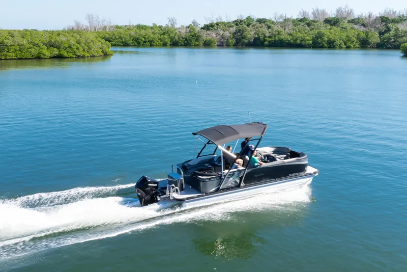 Slide: The Image of 2021 Avalon LSZ Quad Lounger boat cruising on a serene lake with lush greenery. - 19