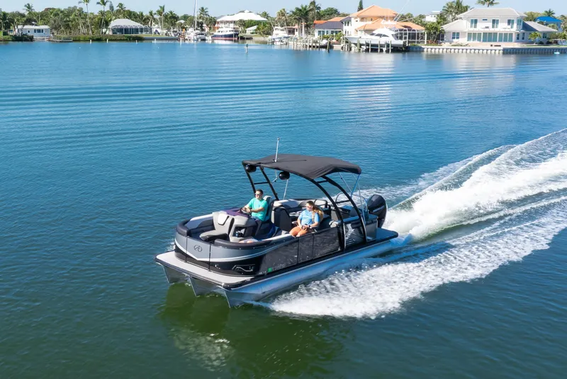 Slide: The Image of 2021 Avalon LSZ Quad Lounger 24' cruising on a serene lake with waterfront homes. - 21