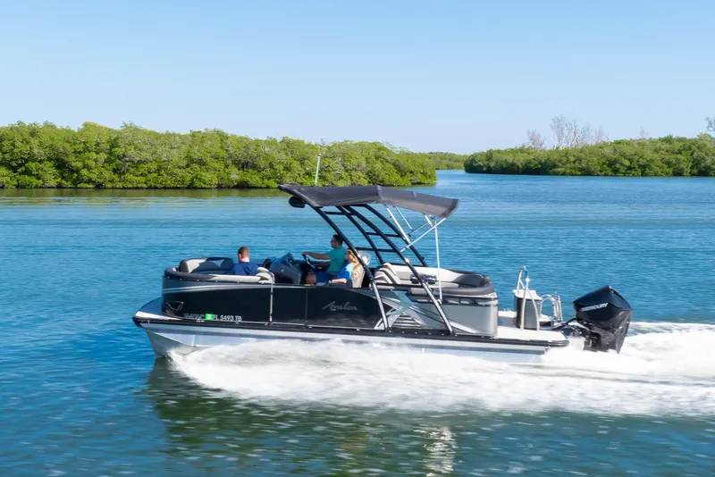 Slide: The Image of 2021 Avalon LSZ Quad Lounger boat cruising on a serene lake with lush greenery. - 23