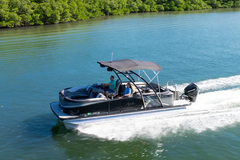 Slide: The Image of 2021 Avalon LSZ Quad Lounger 24' pontoon boat cruising on a serene lake. - 25