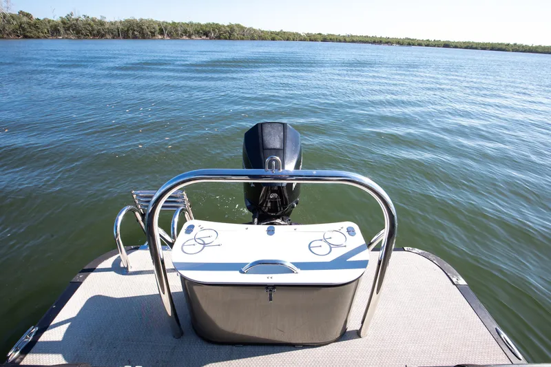 Slide: The Image of 2021 Avalon LSZ Quad Lounger boat on calm water, rear view with motor. - 34
