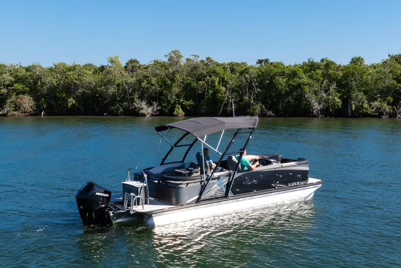Slide: The Image of 2021 Avalon LSZ Quad Lounger boat cruising on a serene lake with lush greenery. - 6