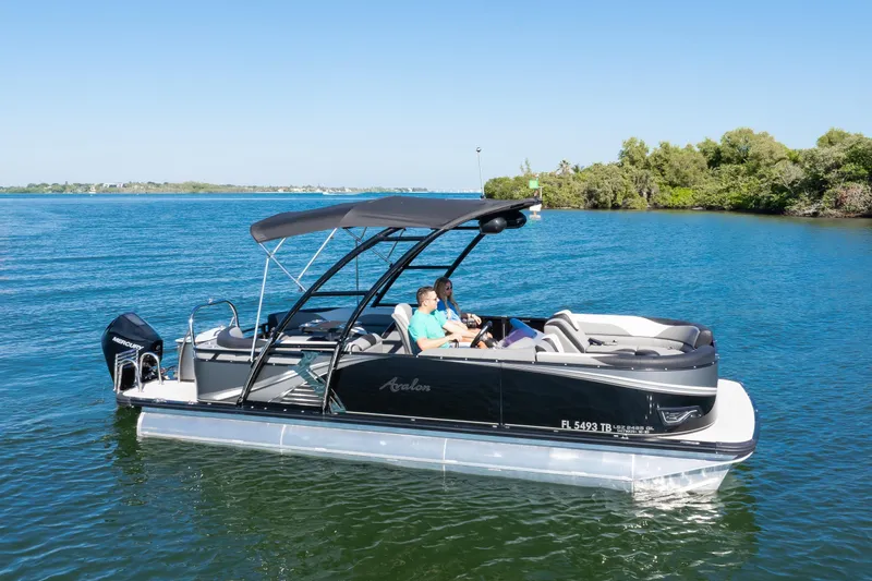 Slide: The Image of 2021 Avalon LSZ Quad Lounger 24' pontoon boat cruising on a serene lake. - 8