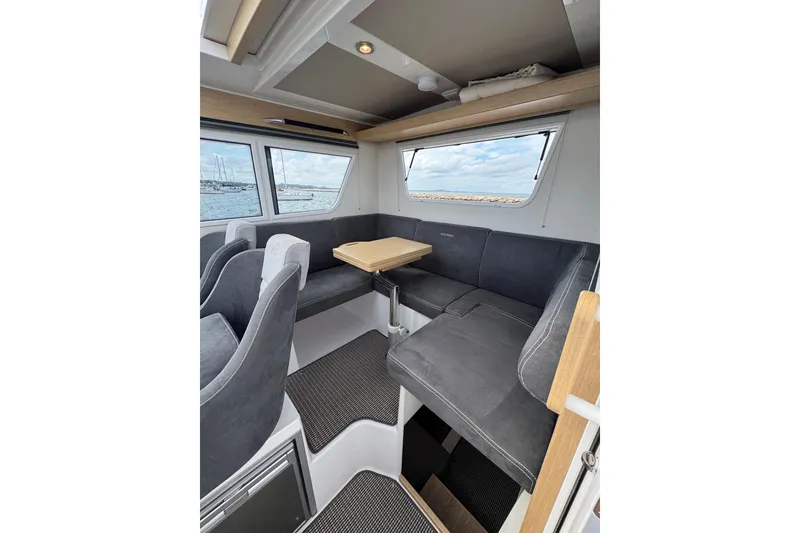 Slide: The Image of Interior of 2025 Sargo 28 yacht with gray seating and wooden table. - 11